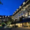 Exterior of a modern hotel at night, illuminated facade with trees along the curved driveway and entrance lights